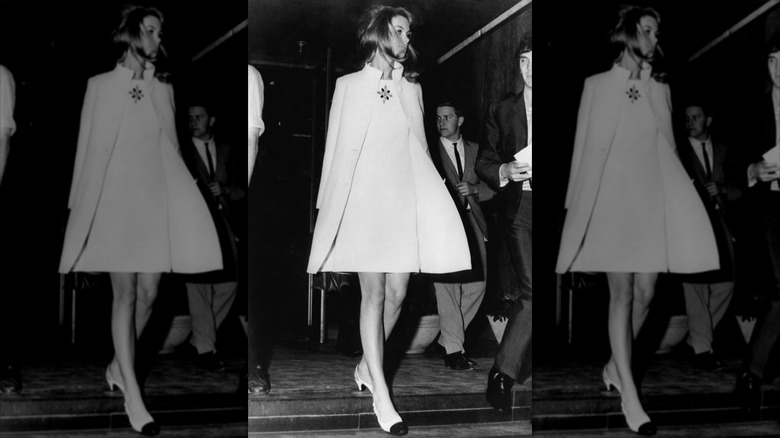 Jean Shrimpton marche vêtue d'une mini-robe blanche