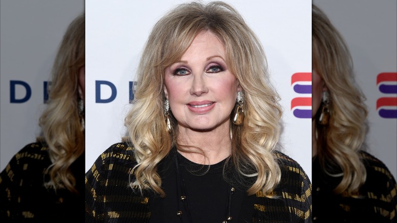 Morgan Fairchild vêtue de noir lors d'un événement en 2019 avec des cheveux légèrement bouclés.