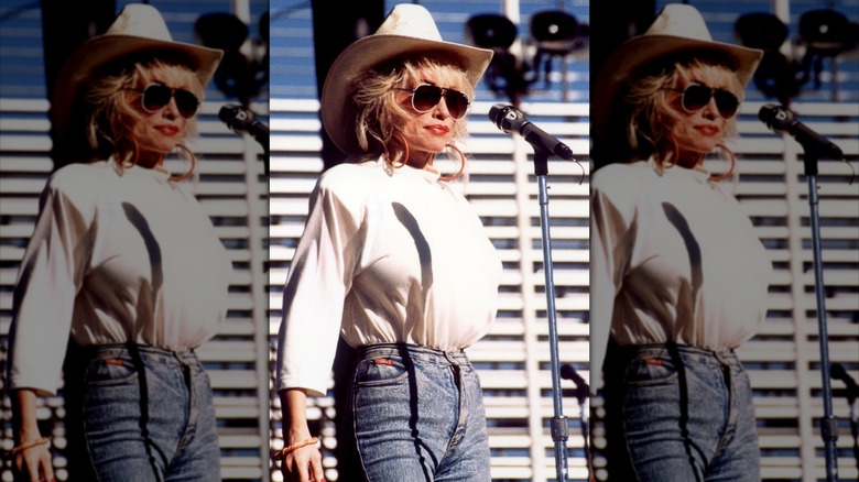 Dolly Parton portait un haut blanc, un chapeau de cow-girl assorti et un jean.