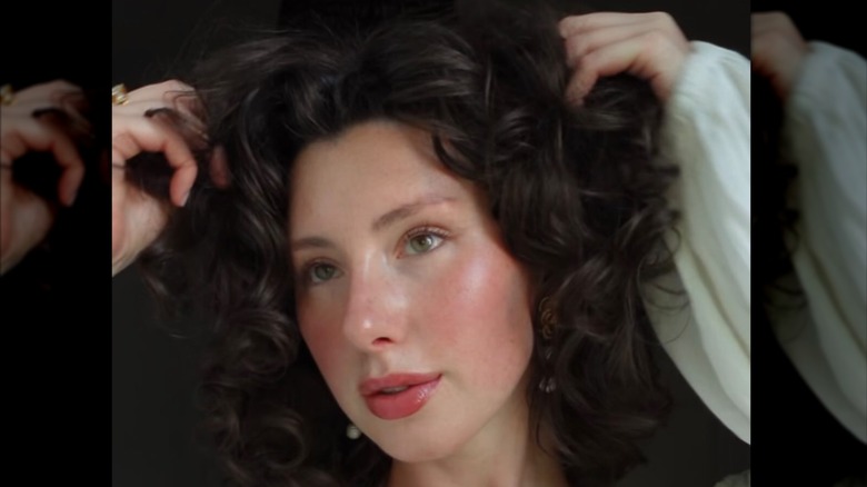 Une personne avec un maquillage cottagecore romantique et des cheveux bouclés