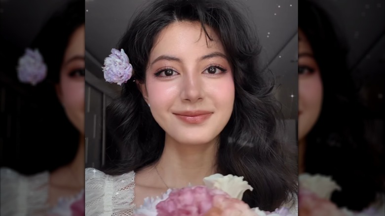 Une personne avec un maquillage cottagecore inspiré des fleurs et souriante
