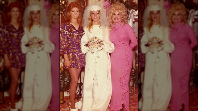 Judy Ogle (à gauche) portant une robe violette avec de longs cheveux roux à côté de Freida Parton (au milieu) et Dolly Parton (à droite)
