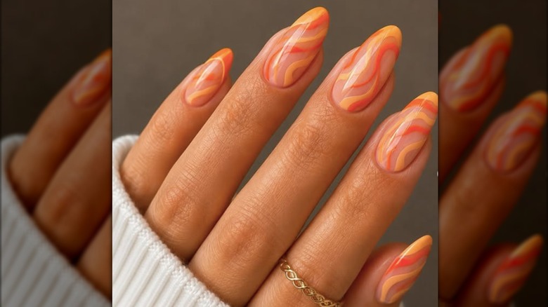 Manucure en forme d'amande peinte de tourbillons de vernis orange clair et foncé