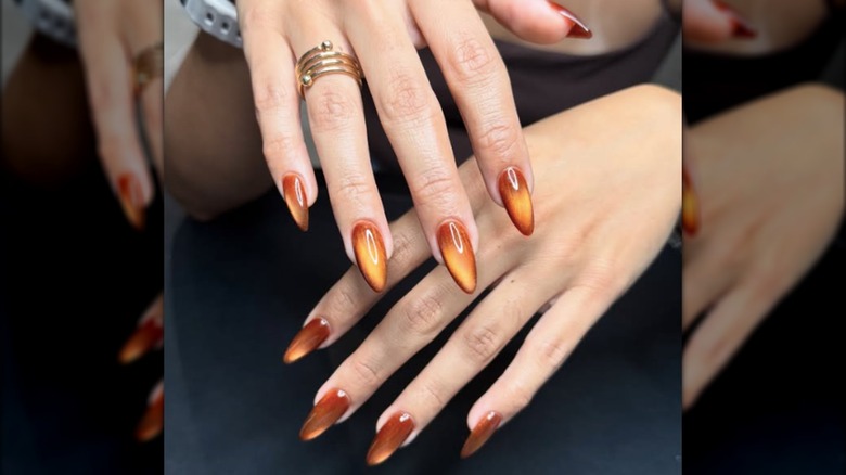 Manucure œil de chat avec motifs orange et ambre
