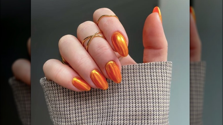 Manucure ronde courte avec vernis à ongles chrome orange