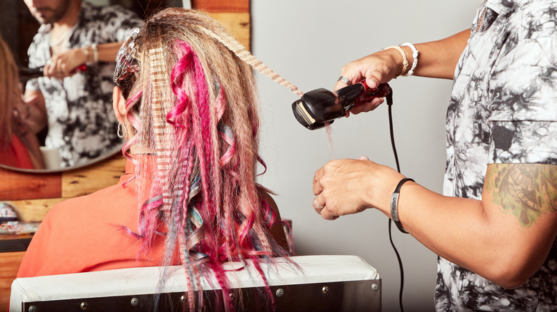 Un styliste frisant les cheveux colorés