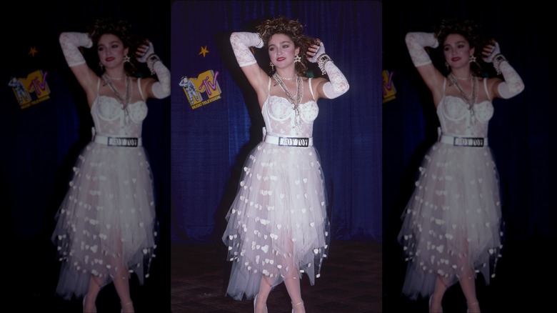 Madonna photographiée en 1984 portant un body en dentelle blanche, une jupe transparente et des gants blancs