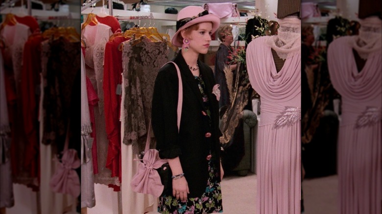 Molly Ringwald photographiée dans le rôle d'Andie Walsh portant un blazer noir, une robe à fleurs et un chapeau rose dans Pretty in Pink