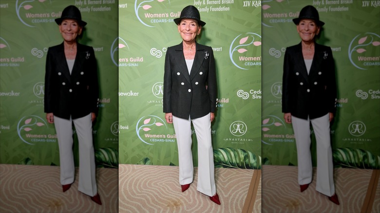 Judy Sheindlin porte un chapeau fedora noir avec un tailleur-pantalon noir et crème.