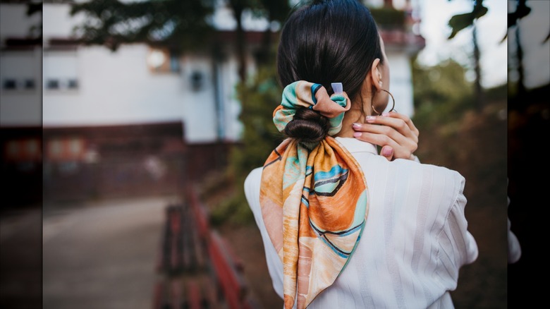 Une femme brune portant ses cheveux en chignon avec un chouchou style bandana