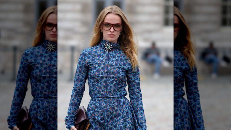 Une jeune fille blonde portant une robe bleue à fleurs et une broche ornée