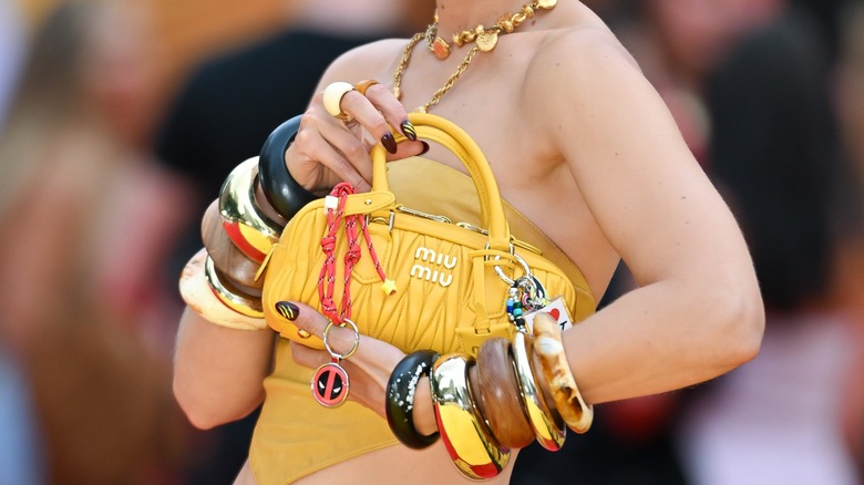 Gigi Hadid tenant une Miu Miu jaune portant des piles de bracelets