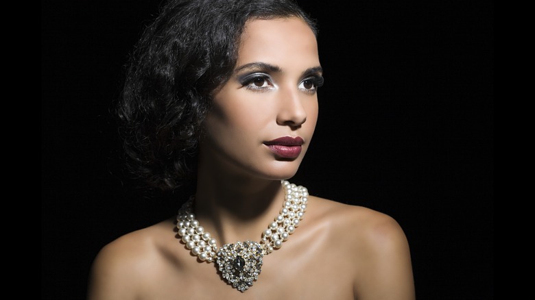 Une femme brune avec un carré portant un tour de cou en perles et cristaux