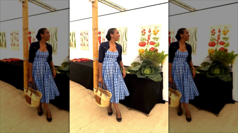 Paula Sutton portant une robe midi à carreaux bleu et blanc et un boléro bleu marine