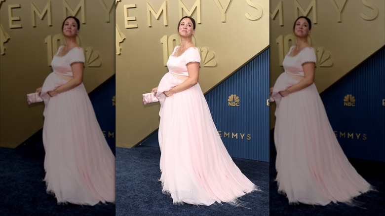 Kaley Cuoco pose avec sa main sur son baby bump sur le tapis rouge
