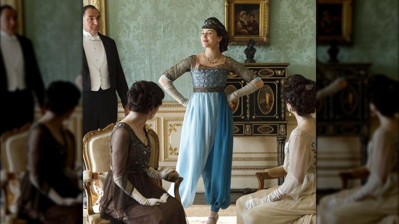 Jessica Brown Findlay dans le rôle de Lady Sybil portant un sarouel turquoise et un bandeau marron