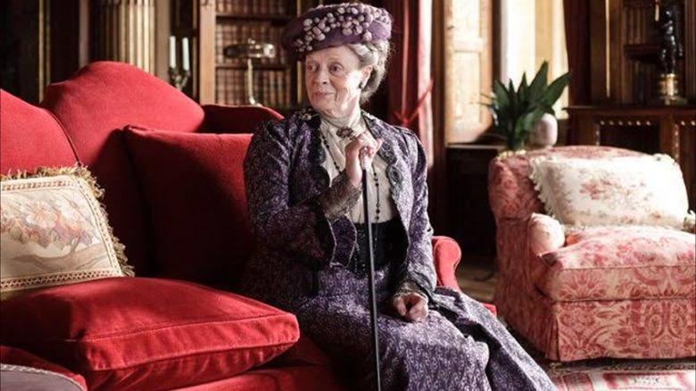 Maggie Smith dans le rôle de Violet Crawley portant une tenue violette de style victorien à Downton Abbey