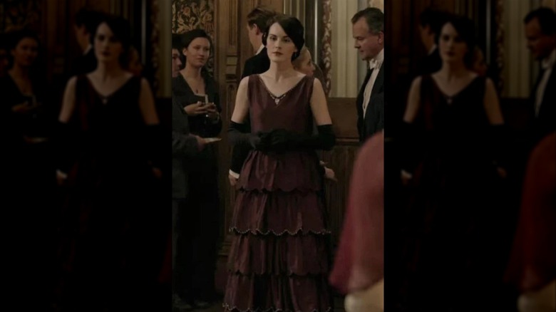 Michelle Dockery dans le rôle de Lady Mary portant une robe bustier bordeaux et de longs gants noirs