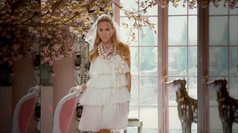 Sarah Jessica Parker dans le rôle de Carrie Bradshaw portant une robe de mariée à volants en tulle et un mini voile.