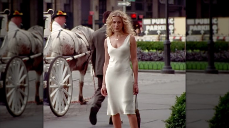Sarah Jessica Parker dans le rôle de Carrie Bradshaw portant une robe nuisette en satin blanc cassé.