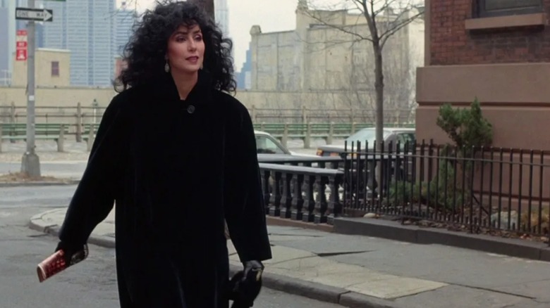 Cher portant un long manteau noir avec des cheveux noirs bouclés dans une rue de New York à 